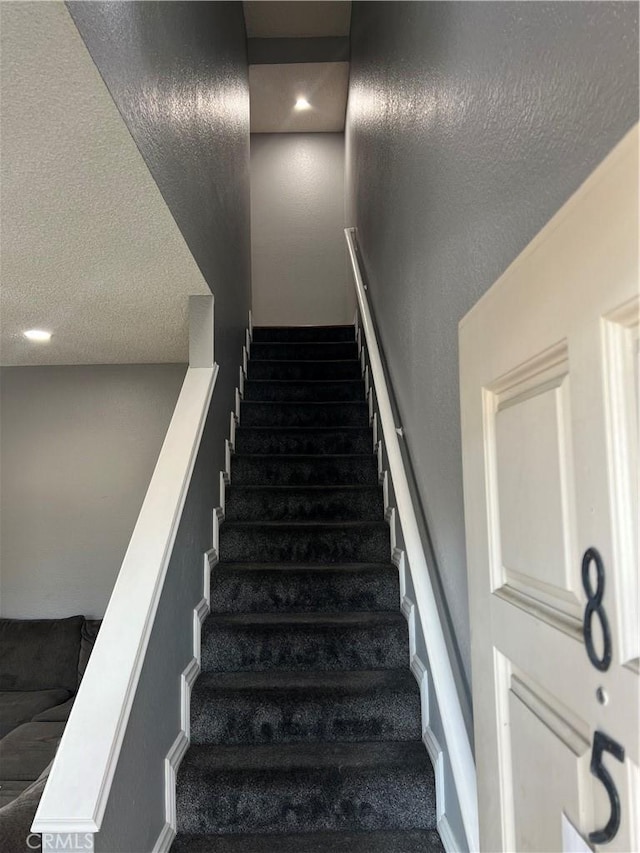 stairs featuring a textured ceiling