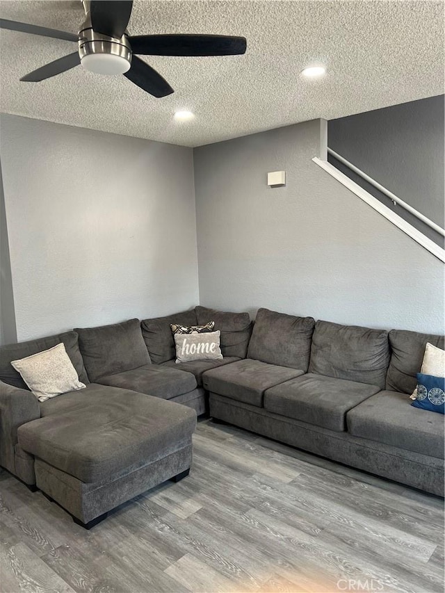 living area featuring a textured ceiling, wood finished floors, and a ceiling fan