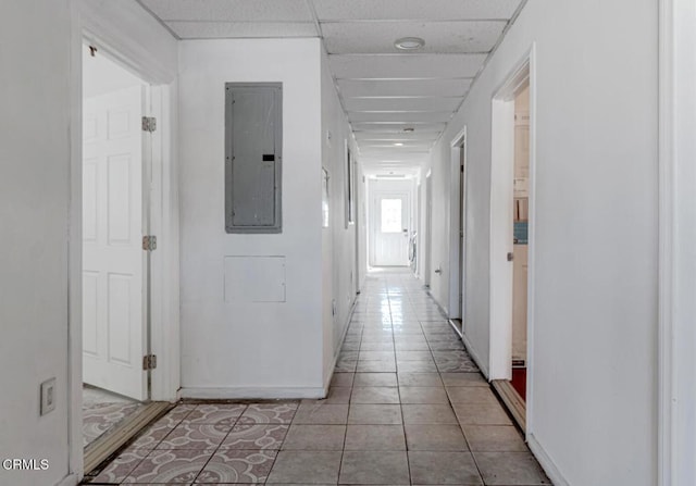 hallway featuring light tile patterned floors, a drop ceiling, and electric panel