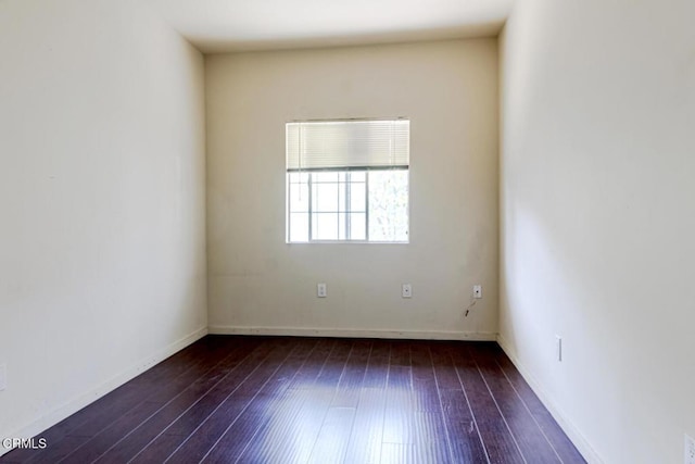 spare room featuring wood-type flooring and baseboards