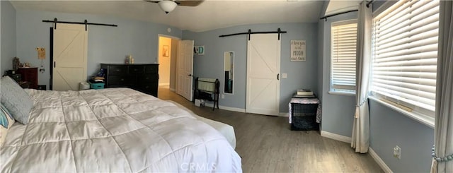 bedroom with wood finished floors, baseboards, and a barn door