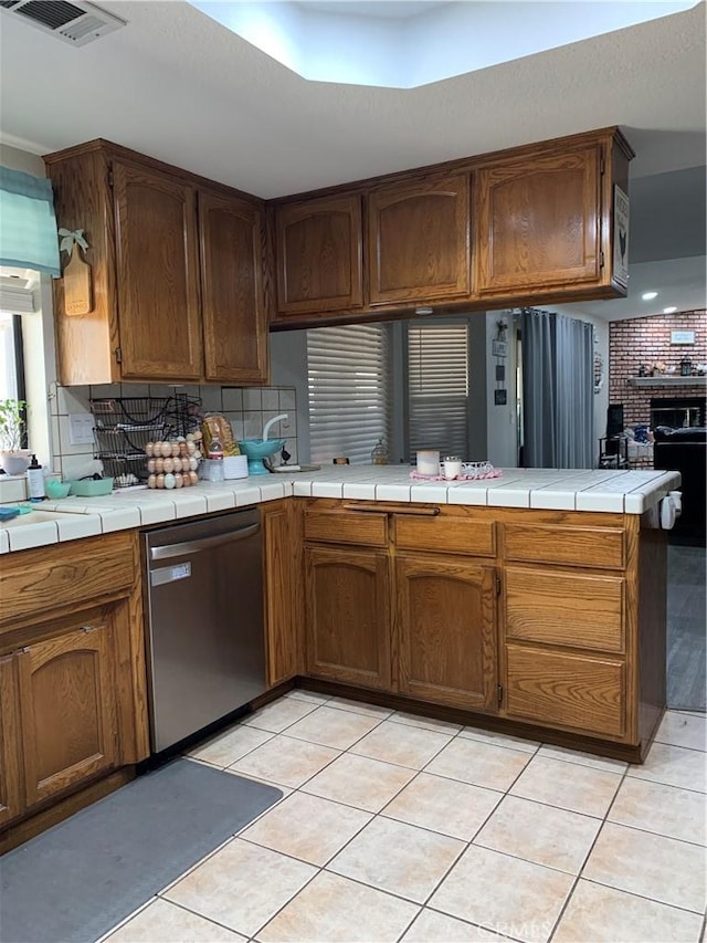 kitchen with dishwasher, tile counters, backsplash, and visible vents