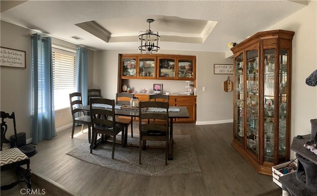 dining space featuring visible vents, a tray ceiling, and dark wood-type flooring