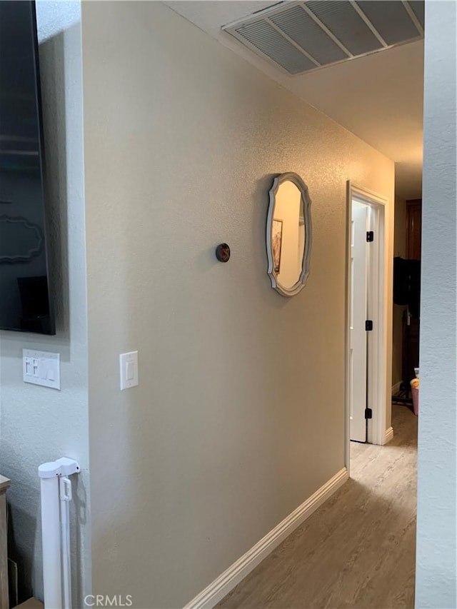 corridor featuring light wood finished floors, baseboards, and visible vents