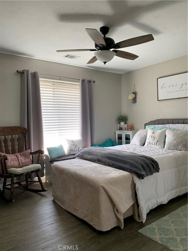 bedroom featuring dark wood-style flooring, visible vents, and ceiling fan