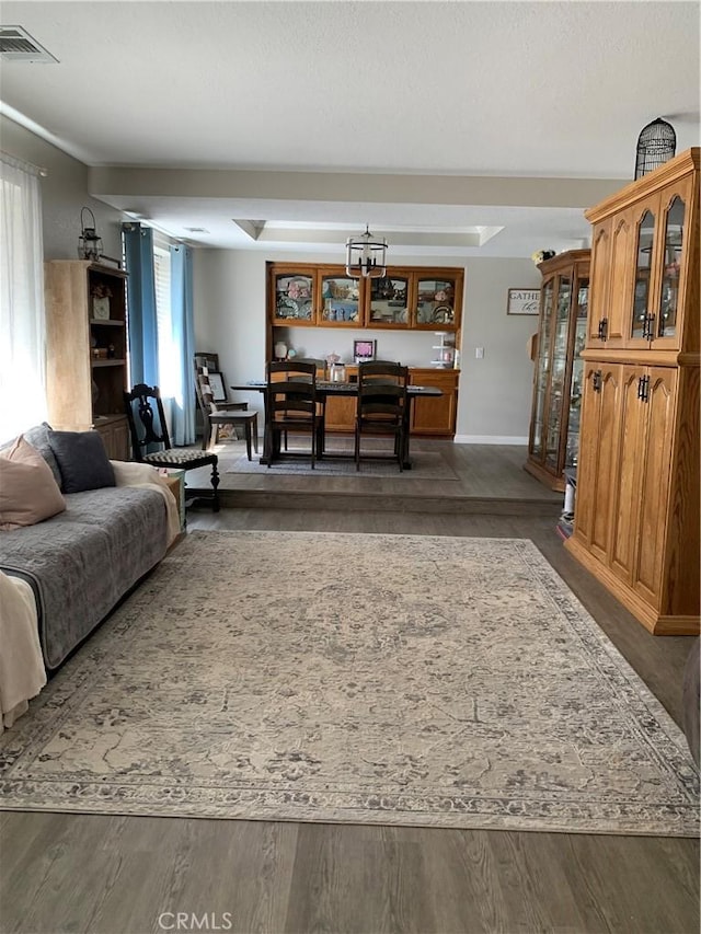 living area with wood finished floors, visible vents, and baseboards