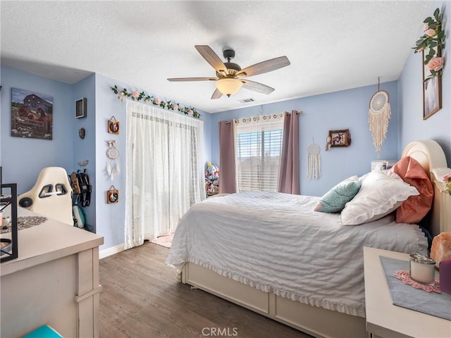 20312 Eyota Rd, Apple Valley, CA 92308 - bedroom with visible vents, dark wood-type flooring, a textured ceiling, baseboards, and ceiling fan