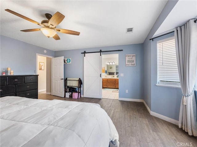 20312 Eyota Rd, Apple Valley, CA 92308 - bedroom with visible vents, connected bathroom, baseboards, a barn door, and wood finished floors