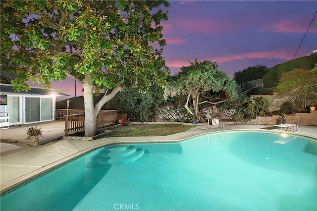 pool at dusk with a fenced in pool, a patio, and fence