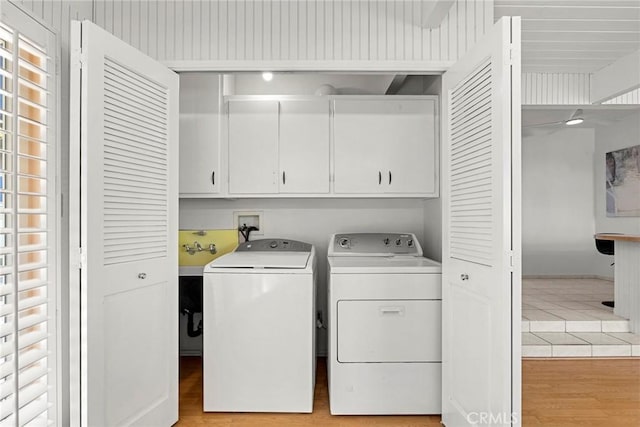 laundry area with light wood-style flooring, cabinet space, and washer and clothes dryer