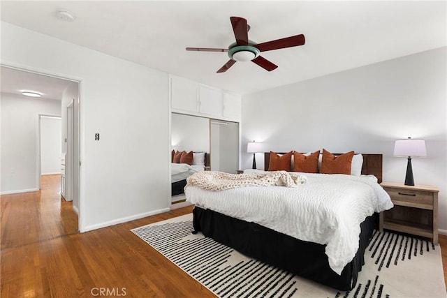 bedroom featuring a closet, baseboards, light wood-style floors, and ceiling fan