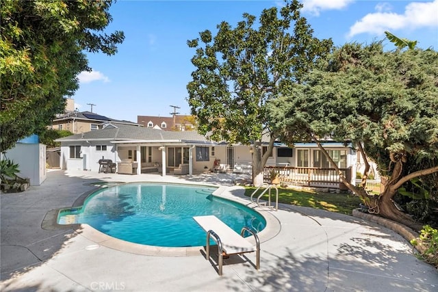 pool featuring a diving board, a patio, and fence