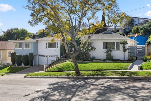 view of front of property featuring stucco siding, driveway, stairway, a front yard, and an attached garage