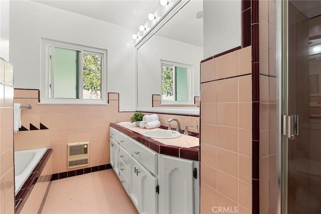 bathroom with heating unit, a healthy amount of sunlight, tile walls, and a sink