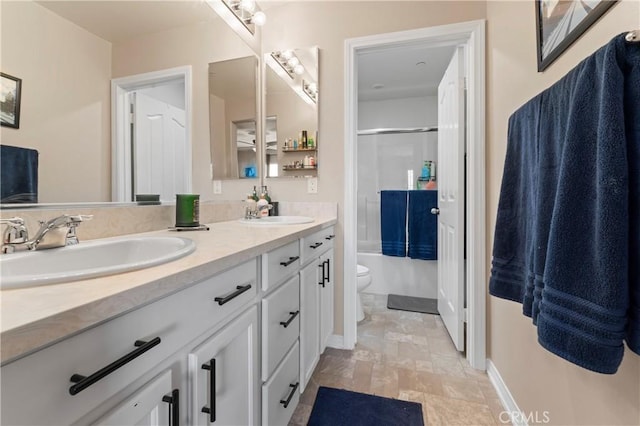 bathroom with double vanity, a sink, toilet, and baseboards