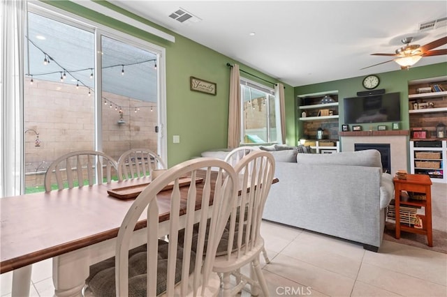 dining space featuring built in shelves, visible vents, a fireplace, and light tile patterned floors