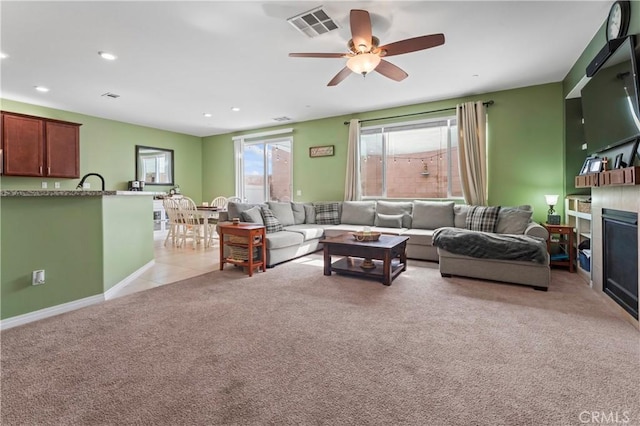 living area with light carpet, a glass covered fireplace, visible vents, and recessed lighting