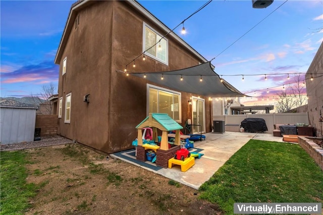 rear view of property featuring an outbuilding, a patio, central AC unit, a fenced backyard, and stucco siding