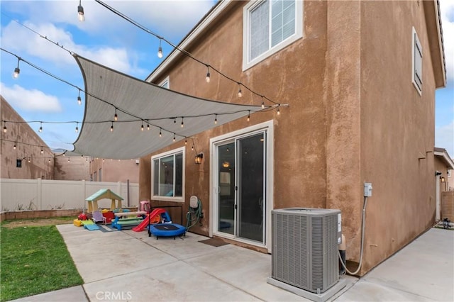 back of property featuring stucco siding, visible vents, a patio area, central AC, and fence private yard