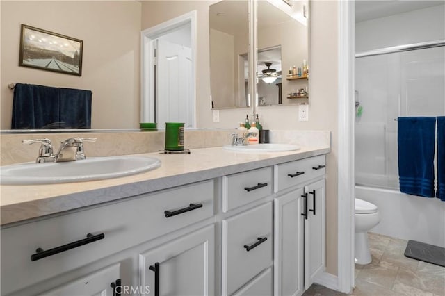 bathroom featuring double vanity, toilet, bath / shower combo with glass door, and a sink