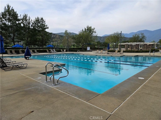 community pool featuring a mountain view and a patio area