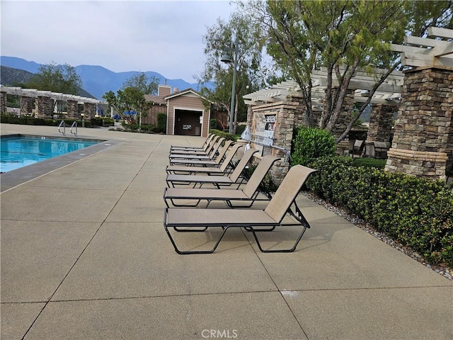 community pool with a mountain view and a patio