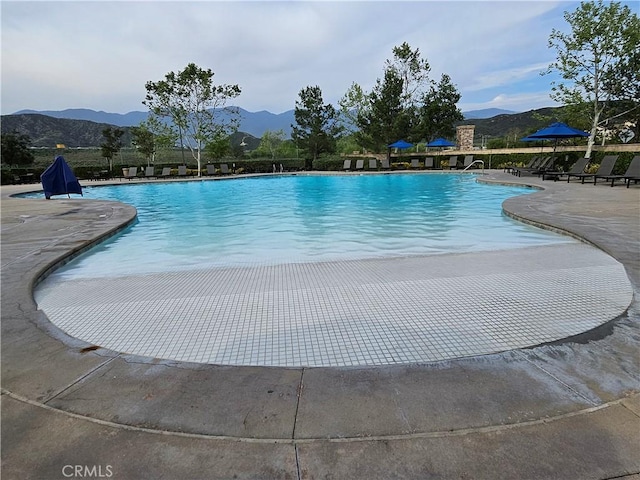 community pool featuring a mountain view and a patio area