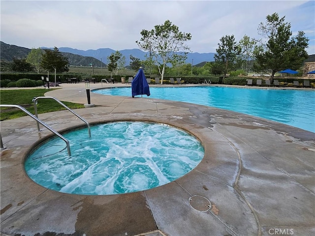 community pool with a mountain view, a community hot tub, and a patio
