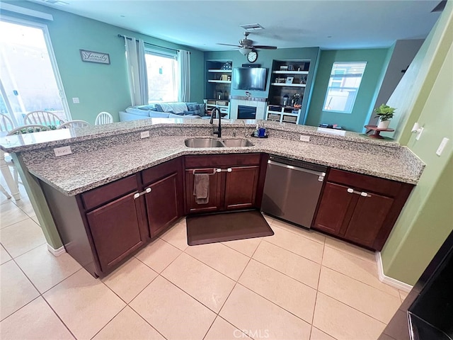 kitchen with stainless steel dishwasher, a sink, a ceiling fan, open floor plan, and light stone countertops