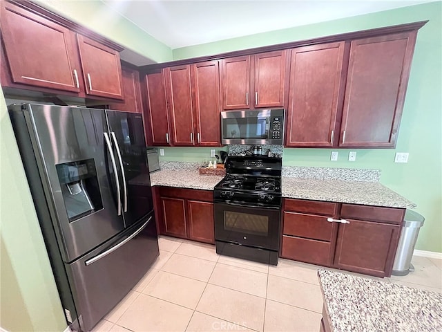 kitchen featuring stainless steel appliances, light tile patterned flooring, light stone countertops, and dark brown cabinets