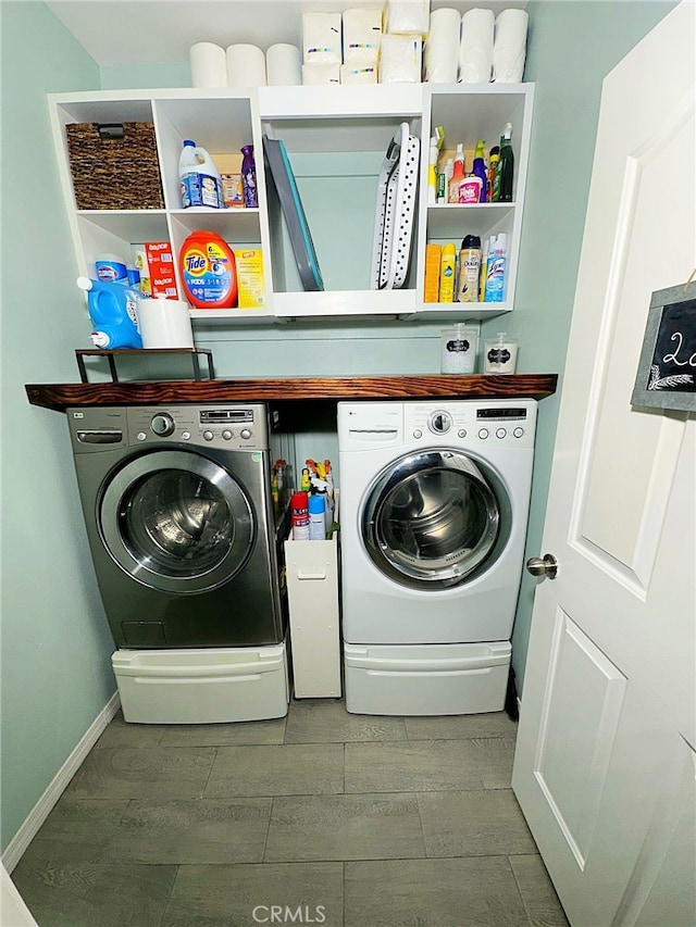 clothes washing area with separate washer and dryer and baseboards