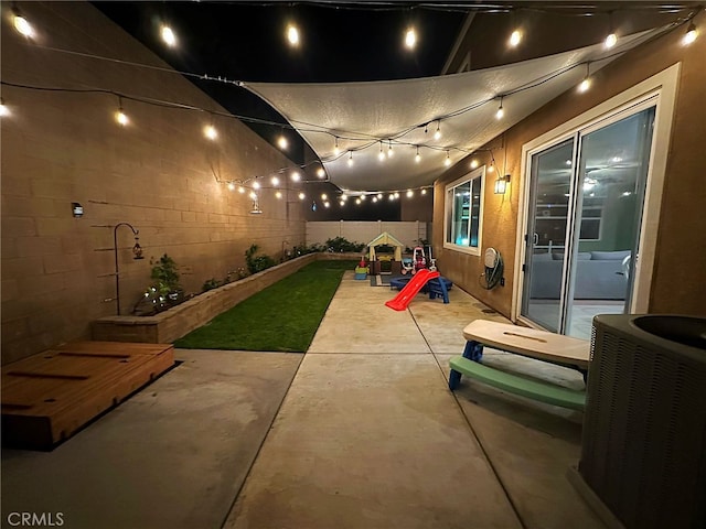 patio at night with central air condition unit and fence