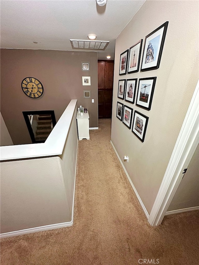 hall featuring light carpet, an upstairs landing, and baseboards