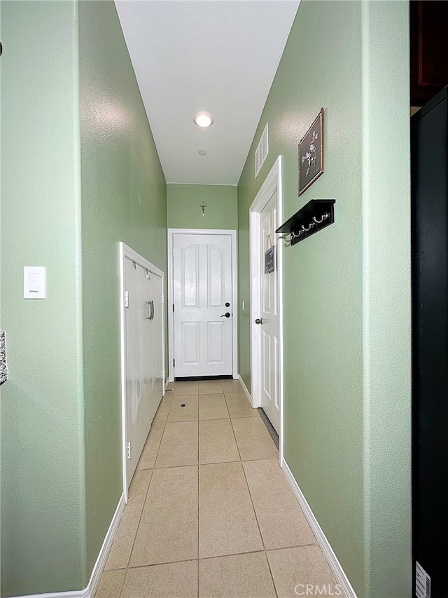 hall featuring light tile patterned floors and baseboards