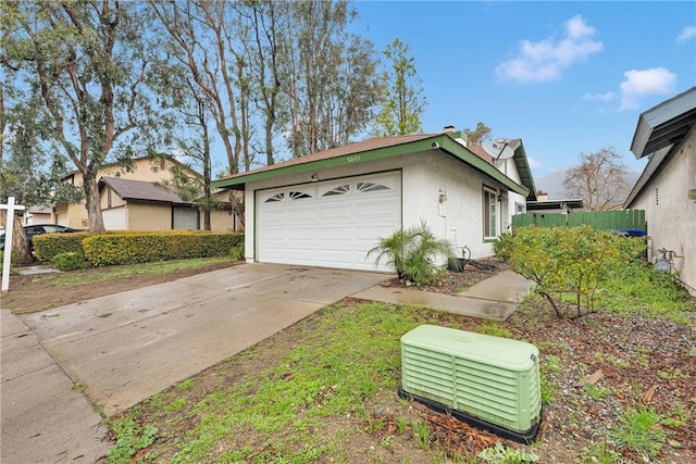 view of home's exterior with driveway, an attached garage, fence, and stucco siding