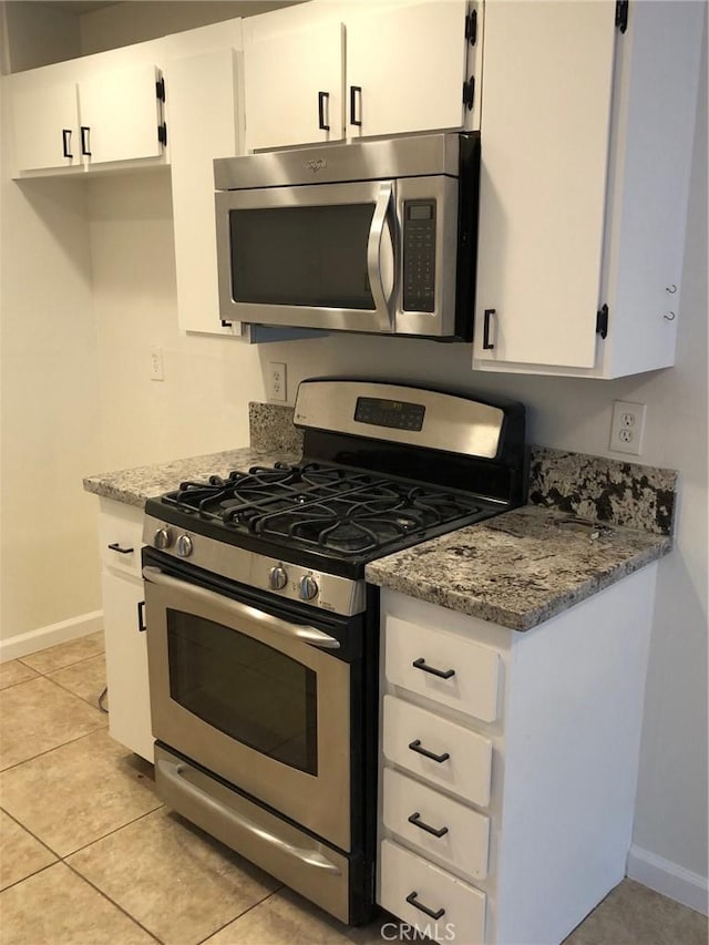 kitchen featuring baseboards, white cabinets, light stone countertops, stainless steel appliances, and light tile patterned flooring