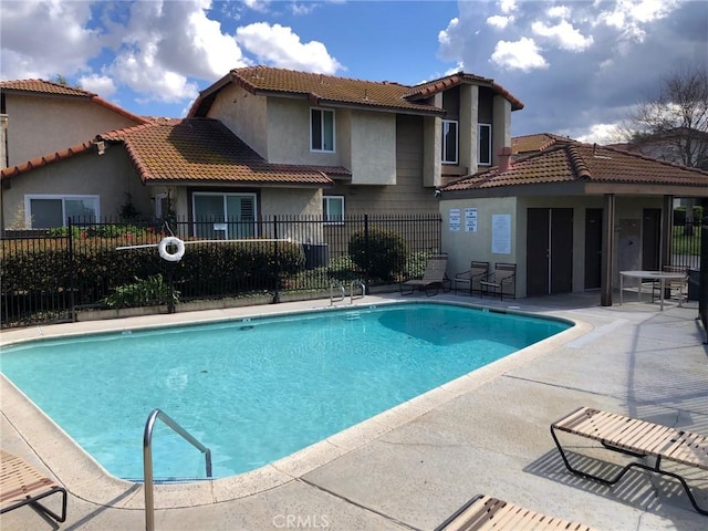 community pool with a patio area and fence