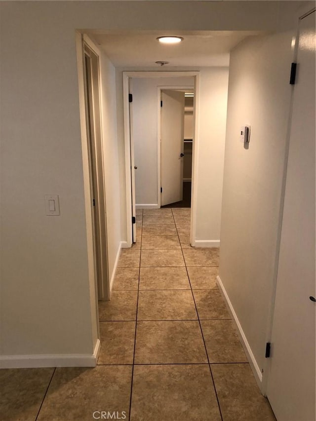 hallway with light tile patterned floors and baseboards