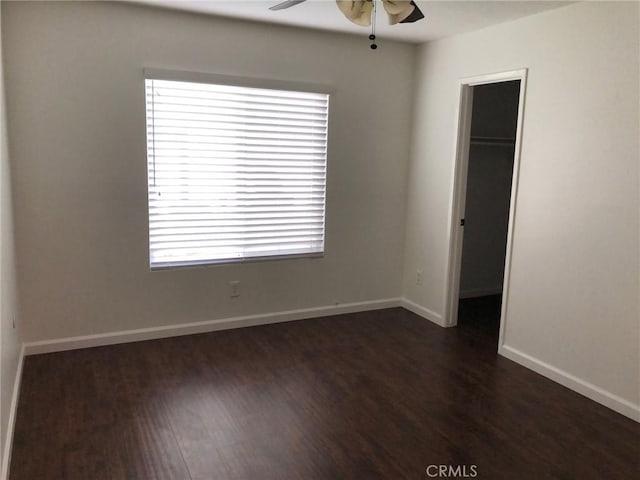 empty room featuring dark wood-type flooring, ceiling fan, and baseboards