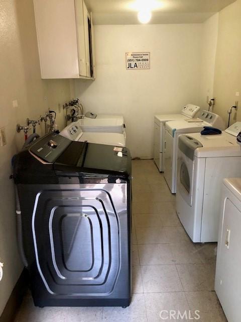 laundry area with washing machine and dryer, light tile patterned flooring, and cabinet space