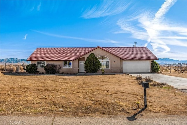 ranch-style home featuring a garage, concrete driveway, a tile roof, a mountain view, and stucco siding