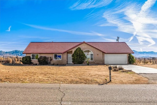 view of front of house with a garage, concrete driveway, a tiled roof, a mountain view, and stucco siding