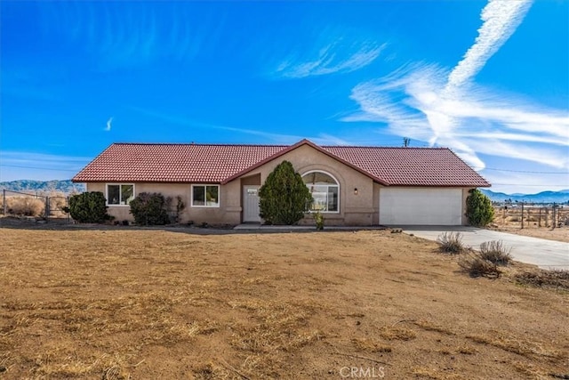 ranch-style house with a tile roof, stucco siding, an attached garage, driveway, and a front lawn