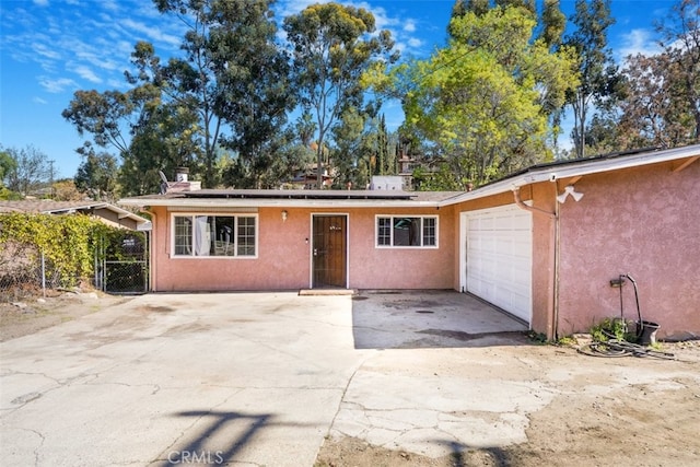 single story home featuring driveway, a garage, a gate, roof mounted solar panels, and stucco siding