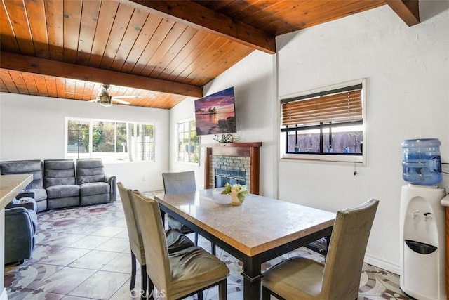 dining space with lofted ceiling with beams, a brick fireplace, wood ceiling, and light tile patterned floors