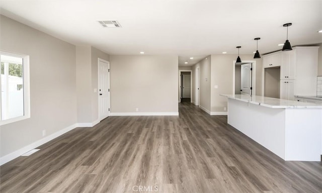 unfurnished living room with light wood-type flooring, visible vents, and baseboards