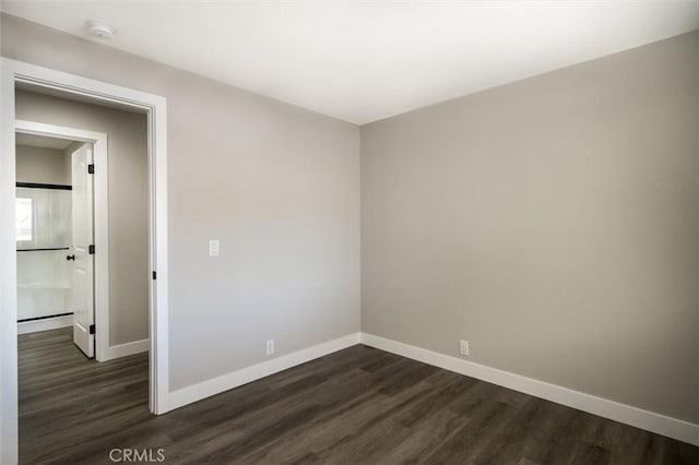 unfurnished room with dark wood-style floors and baseboards