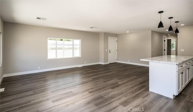 kitchen with light stone counters, pendant lighting, visible vents, open floor plan, and baseboards