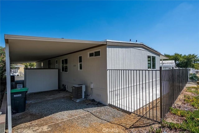 view of home's exterior with crawl space, fence, an attached carport, and central AC