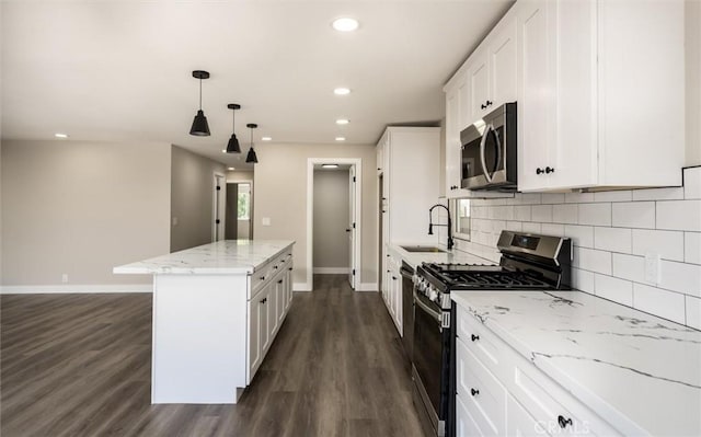 kitchen with stainless steel appliances, white cabinetry, a kitchen island, and a sink